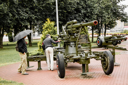 Vitebsk, Belarus - July 1, 2018: Two male tourists view an exhibition of Soviet military equipment of world war II on Victory square on a rainy summer day. 85 mm anti aircraft gun of the 1939 modelのeditorial素材