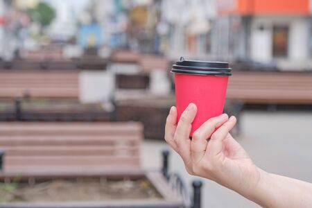 Mature womans hand holds red paper cupの写真素材