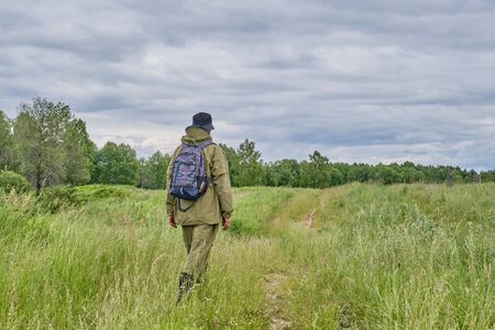 Active man in mosquito suit with backpack in hiking in a meadow. Siberia, Russia. Solo traveling,...
