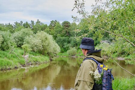 Active man in mosquito suit with backpack in hiking near taiga river in a siberian forest, Russia. Solo traveling, lifestyle, domestic tourism conceptの写真素材