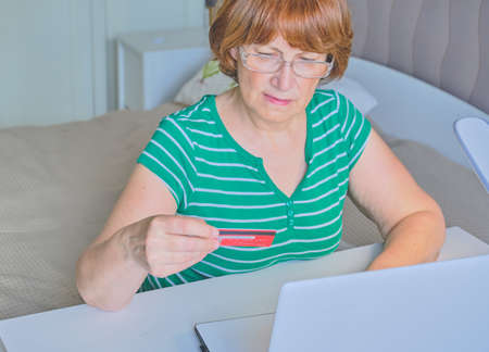 Senior woman using a laptop in her bedroom at home. Happy retired person shopping online on the bed. Lifestyle Copy spaceの写真素材