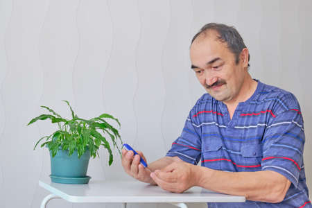 Senior man checking blood sugar level at homeの写真素材