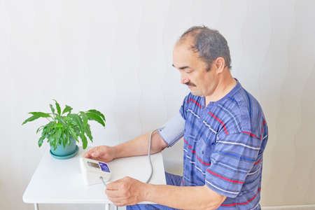 Senior man checking blood pressure using an electronic tonometer at home Copy spaceの写真素材