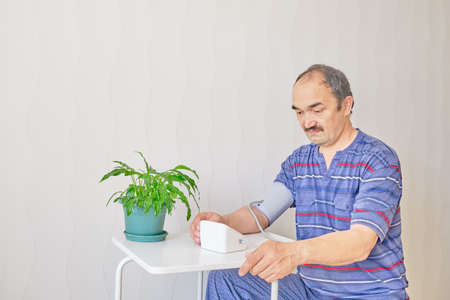 Senior man checking blood pressure using an electronic tonometer at home Copy spaceの写真素材