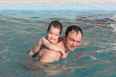 Happy father and son spend time together swimming in the thermal pool.の写真素材