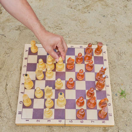 A hand of senior man making a move in a game of chess on background of the sandy beach. Digital detox conceptの写真素材