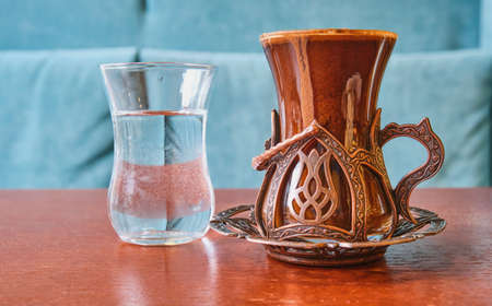 Fresh strong Turkish coffee in a beautiful glass in Oriental style and a glass of water is on the table in the cafeの写真素材