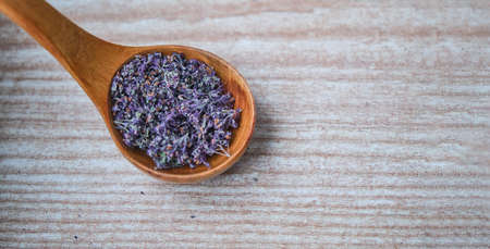 Wooden spoon with dried flowers of oregano on a wooden background. Bannerの写真素材