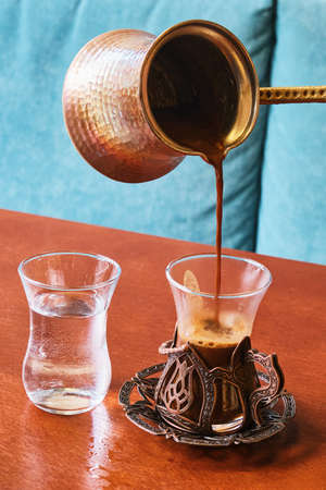Fresh strong Turkish coffee in a beautiful glass in Oriental style and a glass of waterの写真素材