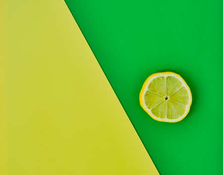Combined yellow-green background. Round slice of yellow lemon on a green background. Top viewの写真素材