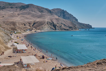 Sudak, Russia - September 12, 2020: People rest on the equipped beach of Cape Meganom on the Black Sea, Crimea peninsulaのeditorial素材