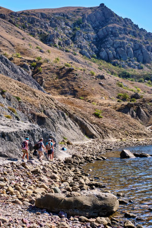 Sudak, Russia - September 12, 2020: Tourists walks along the path of the rocky coast of Cape Meganom on the Black Sea, Crimea peninsula.のeditorial素材
