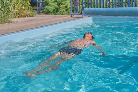 A middle-aged man swims in a pool in the courtyard of a house. Motion blurの写真素材