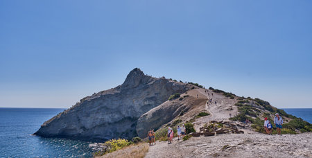 Sudak, Ukraine - September 14,2020: Coastal seascape landscape. People walking along cape Kapchik, Golitsyn trail. Crimean peninsula. National botanical reserve New World. Bannerのeditorial素材
