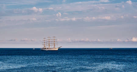 Beautiful three-masted sailboat over the background of the blue sea and cloudy sky.の写真素材