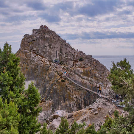 Coastal seascape landscape. Rock Diva, the black sea coast near Yalta, town Simeiz, Crimea. People walk on the suspension bridge, climb to the top.の写真素材