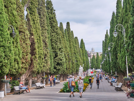 People walk along Cypress alley and relax on benches. Spa town Simeiz, big Yalta, South Coast of Crimea. Apollo Alley, Lenin Avenue.のeditorial素材