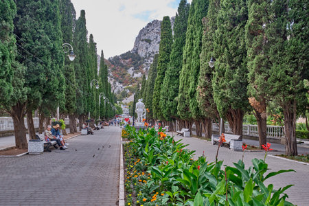 Yalta, Russia - September 19, 2020: People walk along Cypress alley and relax on benches. Spa town Simeiz, big Yalta, South Coast of Crimea. Apollo Alley, Lenin Avenue.のeditorial素材
