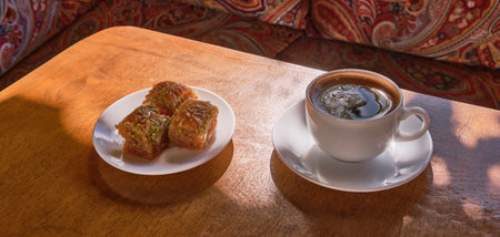 Eastern sweetness, Turkish baklava, black coffee in a white cup on a wooden table.の写真素材
