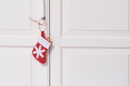 One red and white toy textile sock with Christmas gifts on the cabinet door handle.の写真素材