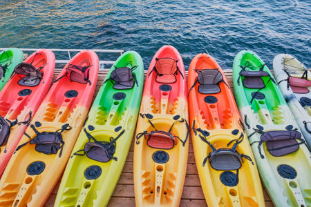 Several multi-colored plastic kayak boats on a wooden stage against the backdrop of the sea. View from above.の写真素材