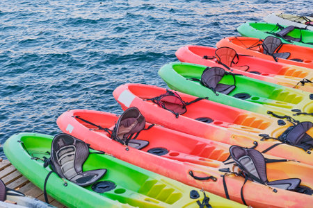 Several multi-colored plastic kayak boats on a wooden stage against the backdrop of the sea. View from above.の写真素材