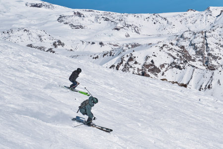 Terskol, Russia - January 24, 2021: Two guys on alpine skiing descends the snowy slope of Cheget mountain.のeditorial素材