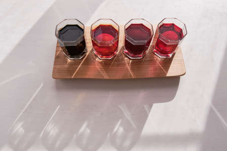 Four eggs in glasses of water in a row on wooden board is coloring with natural dyes in purple, pink, orange, green.の写真素材
