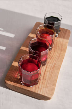 Four eggs in glasses of water in a row on wooden board is coloring with natural dyes in purple, pink, orange, green.の写真素材