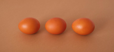 Three painted orange eggs on a brown background. Abstract composition.の写真素材
