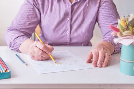 Elderly womans hand painting an abstract pattern from adult coloring pages.の写真素材