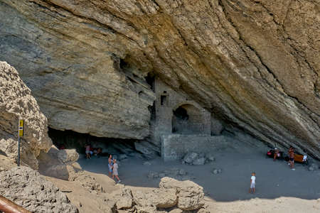 Black Sea coast, Crimea. People are resting in a grotto carved out of the Koba-Kaya mountain by waves. A scenic natural attraction, grotto Golitsynの写真素材