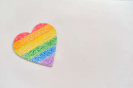 Paper heart painted with colored pencils like a LGBT flag on white background.の写真素材