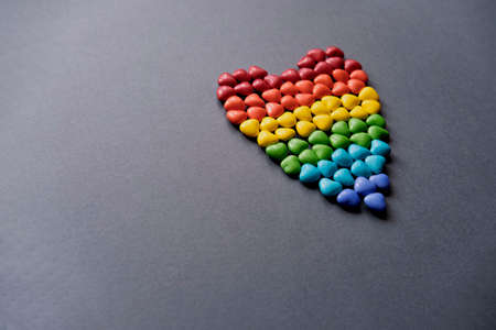 Big heart of small colored candy in the form of hearts like a LGBT flag on gray background.の写真素材