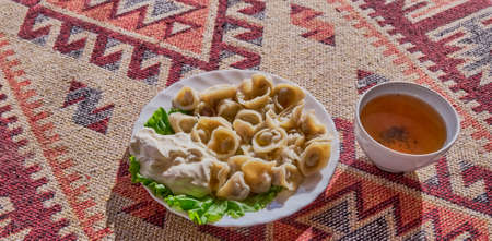 Meat dumplings with sour cream and a cup of hot herbal tea.の写真素材