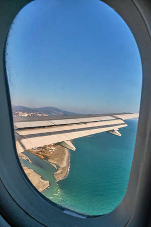 The wing of an airplane flying over the city, the sea and the river. Sochi, Russiaの写真素材