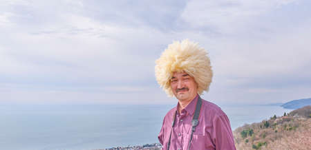 Portrait of an asian man in traditional caucasian hat made of white sheepskin.の写真素材