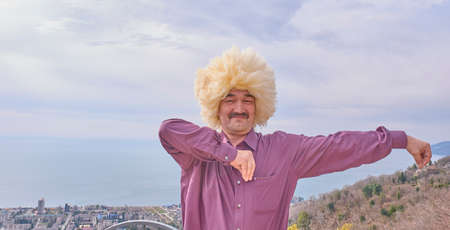 Asian man in traditional caucasian hat is dancing lezginka on the background of the Black sea and the city of Gagra, Abkhaziaの写真素材