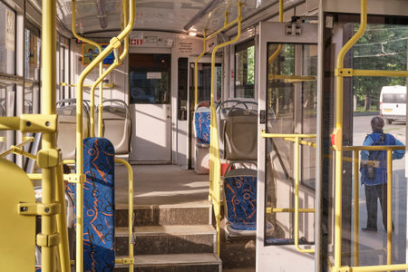 Tram without passengers at a stop with open doors on a sunny summer day. Inside view.のeditorial素材