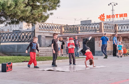 Boys are dancing breakdance on a city street. The solo child is in her arms.のeditorial素材