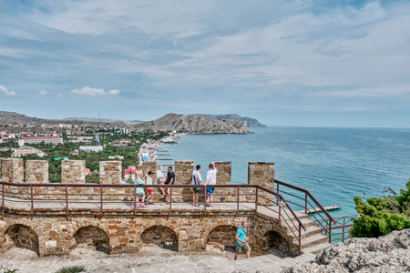 Tourists walking along the wall of an ancient fortress against the backdrop of a seascape.のeditorial素材