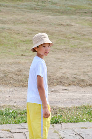 Portrait of an Asian boy in a white T-shirt, yellow trousers and a panama hatの写真素材