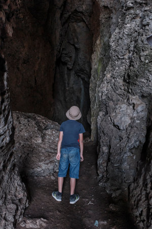 A boy standing inside a through grotto located in the rock, National botanical reserve New World, Crimea.の写真素材