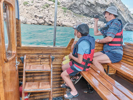 Asian older man and his grandsons trip on pleasure boat on the sea.の写真素材