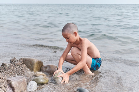 A small tanned Asian boy playing on the seashoreの写真素材