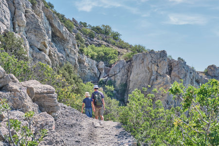 Boy and man hiking on the scenic Golitsyn trail. National botanical reserve New World, Crimea. View from backの写真素材
