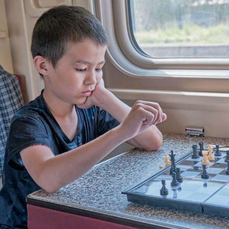 Asian young boy playing chess at train.の写真素材