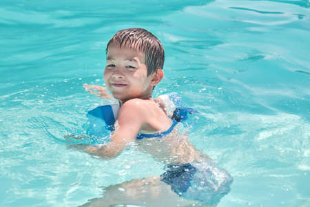 Little asian boy is learning to swim in outdoor poolの写真素材