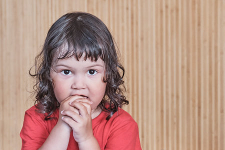 Home portrait of cute asian little girl with his hands near his mouth.の写真素材