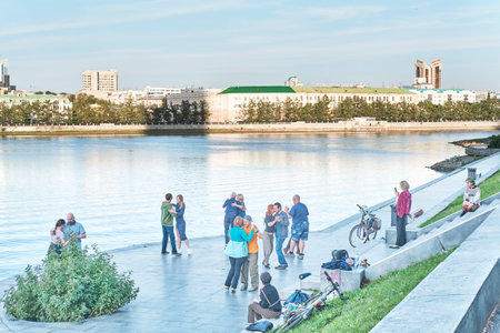 Dancing couples, people walking on embankment of Iset river. Summer city landscape.のeditorial素材